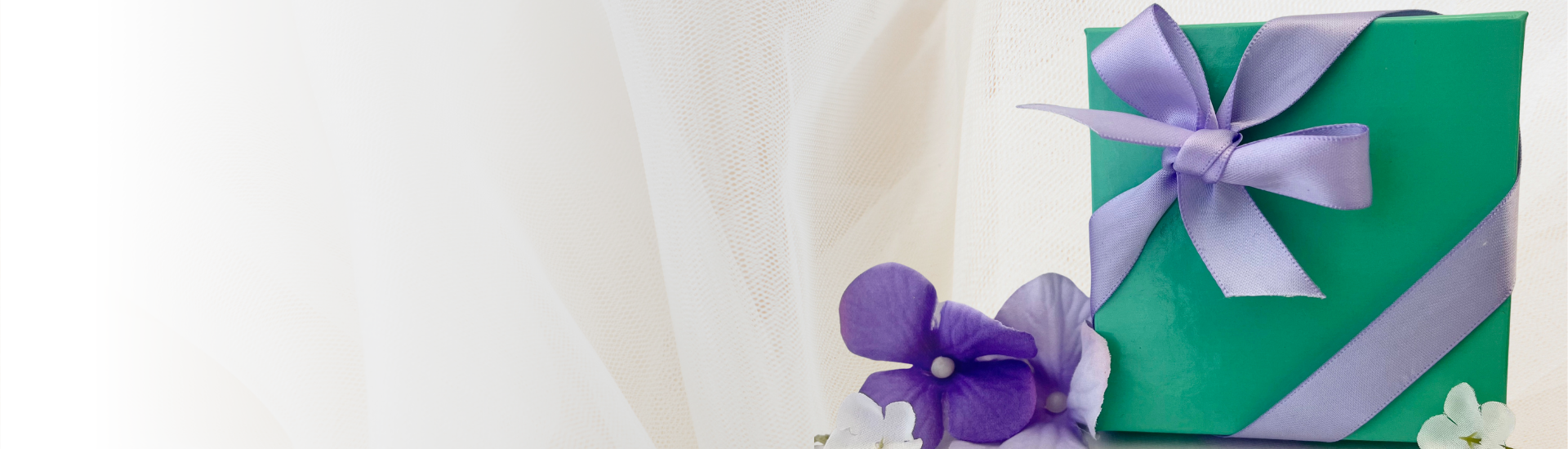 Green box with purple ribbon surrounded by flowers